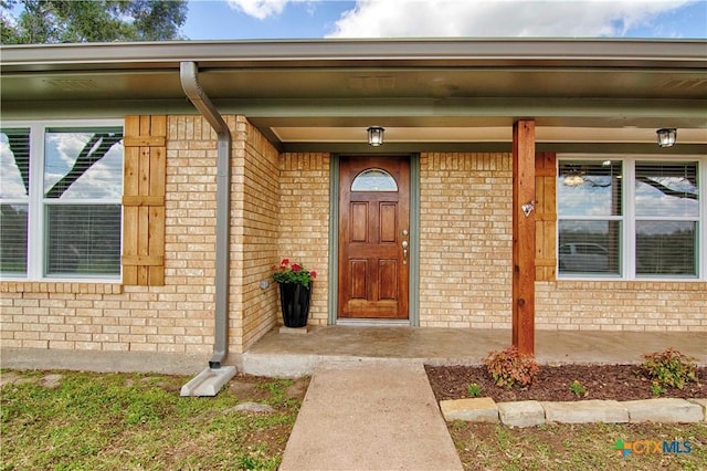 property entrance with brick siding and a porch