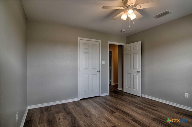 unfurnished bedroom featuring a ceiling fan, baseboards, visible vents, and dark wood-style flooring