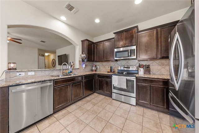 406 Coby, Troy, TX 76579 - kitchen with stainless steel appliances, dark brown cabinets, tasteful backsplash, light stone counters, and arched walkways