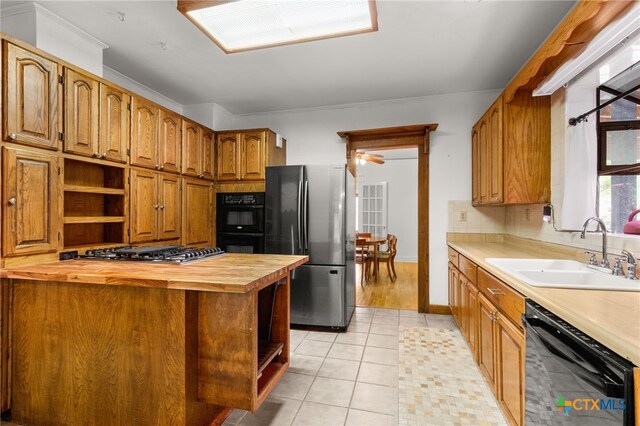 216 E Cedar St, Seguin, TX 78155 - kitchen with black appliances, a sink, wood counters, open shelves, and brown cabinets