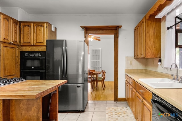216 E Cedar St, Seguin, TX 78155 - kitchen featuring black appliances, a sink, butcher block counters, brown cabinets, and decorative backsplash
