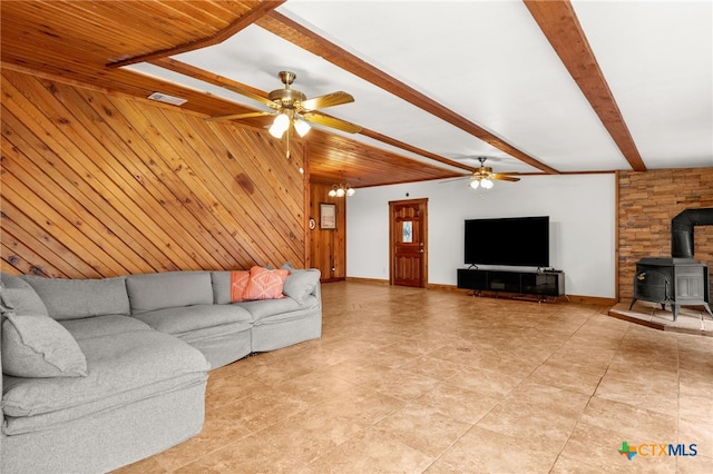 216 E Cedar St, Seguin, TX 78155 - living room with a wood stove, wooden walls, a ceiling fan, beam ceiling, and baseboards