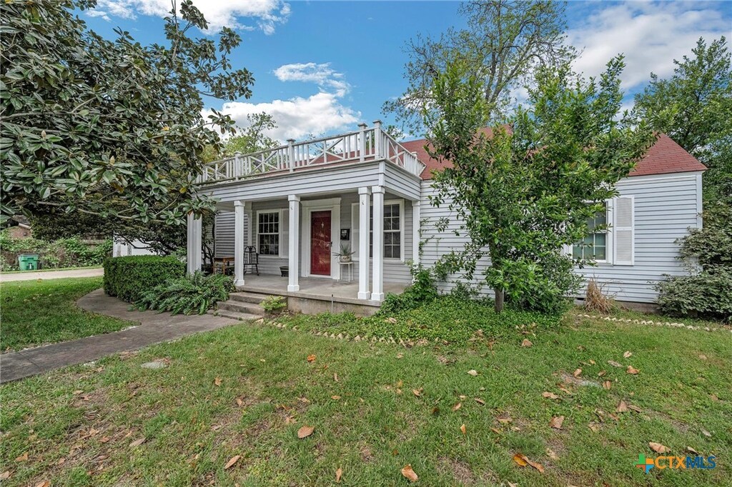 1410 N Cleveland Ave, Cameron, TX 76520 - view of front of home with a balcony, a front yard, and covered porch