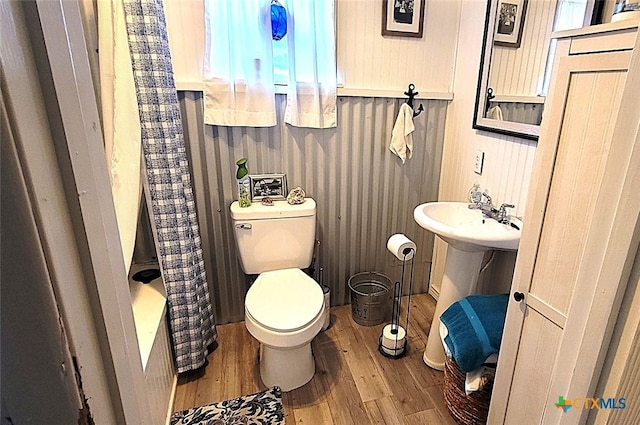full bath featuring wood finished floors, toilet, and curtained shower