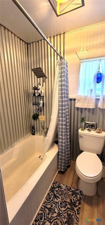 full bath featuring wood finished floors, shower / bath combination with curtain, and toilet