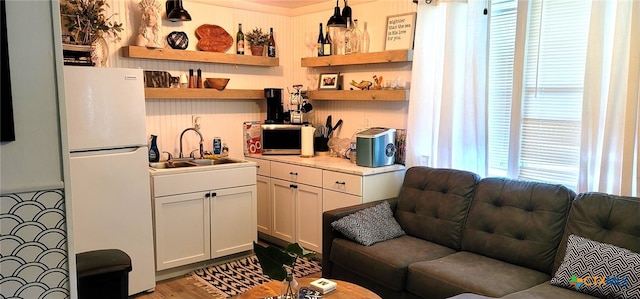 interior space with freestanding refrigerator, a sink, and wood finished floors