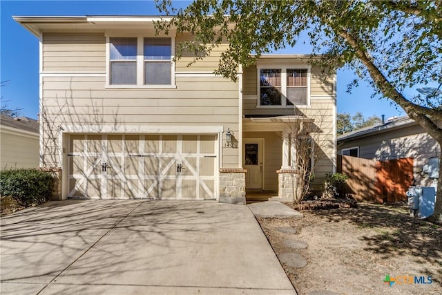 view of front facade featuring a garage, driveway, and fence