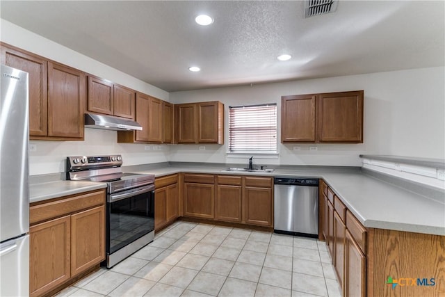 kitchen with visible vents, appliances with stainless steel finishes, brown cabinetry, a sink, and under cabinet range hood