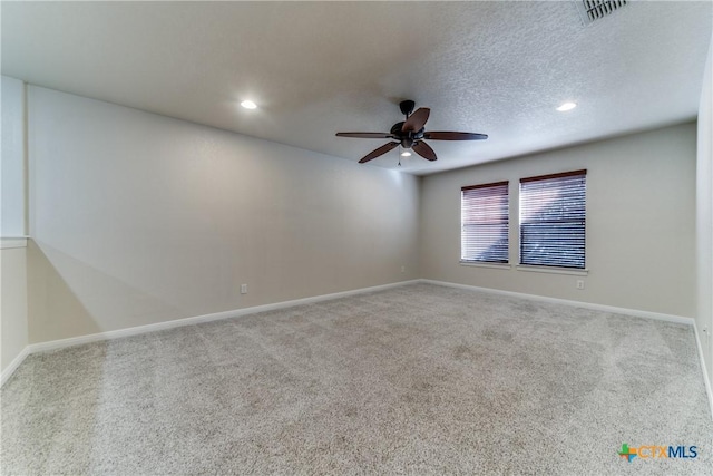 spare room with a textured ceiling, baseboards, visible vents, and light colored carpet