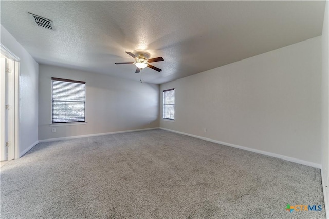 carpeted empty room featuring visible vents, ceiling fan, a textured ceiling, and baseboards