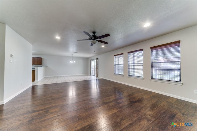 unfurnished living room featuring light wood finished floors, baseboards, ceiling fan with notable chandelier, a textured ceiling, and recessed lighting