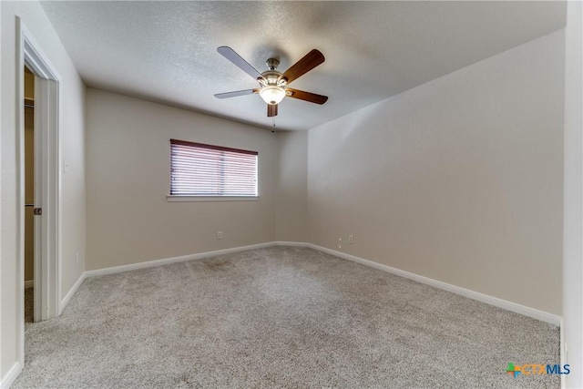 empty room featuring ceiling fan, baseboards, a textured ceiling, and light colored carpet