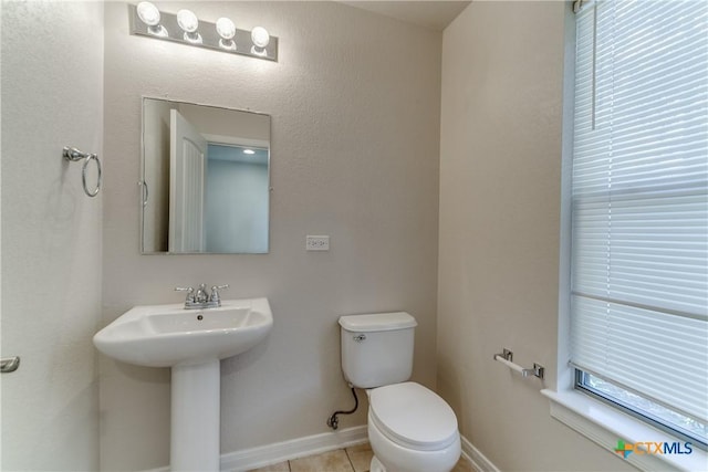 bathroom featuring tile patterned flooring, baseboards, a sink, and toilet