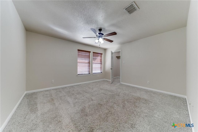 empty room featuring a textured ceiling, ceiling fan, visible vents, and baseboards