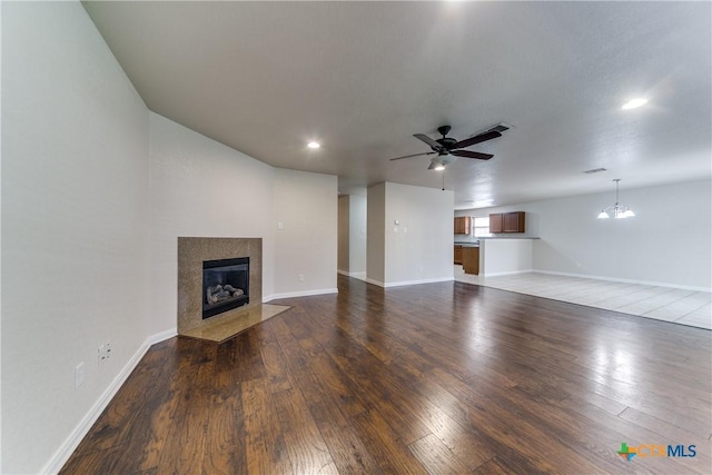 unfurnished living room with baseboards, a premium fireplace, hardwood / wood-style floors, ceiling fan with notable chandelier, and recessed lighting