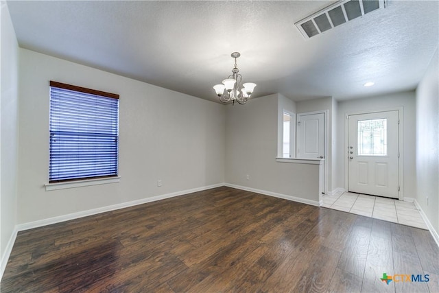 entrance foyer with a notable chandelier, visible vents, a textured ceiling, wood finished floors, and baseboards