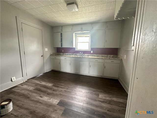 kitchen featuring white cabinets, dark wood-type flooring, sink, and light stone counters