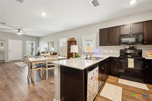 kitchen featuring visible vents, dark brown cabinets, light wood-style floors, a sink, and black appliances