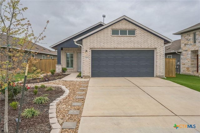 view of front facade with concrete driveway, brick siding, and fence
