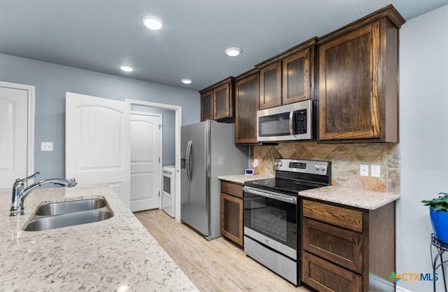 832 Paseo Del Plata, Temple, TX 76502 - kitchen featuring appliances with stainless steel finishes, light wood-style flooring, dark brown cabinets, backsplash, and light stone counters