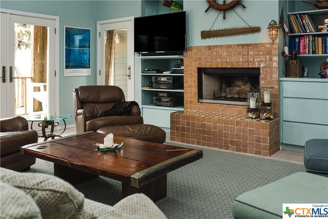 living room featuring a tiled fireplace and french doors