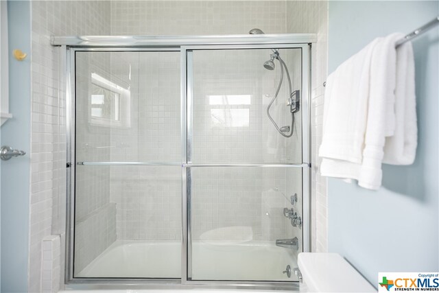 bathroom featuring shower / bath combination with glass door and toilet