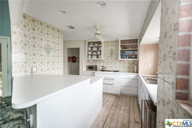 kitchen with white cabinetry, sink, ceiling fan, light hardwood / wood-style flooring, and decorative backsplash