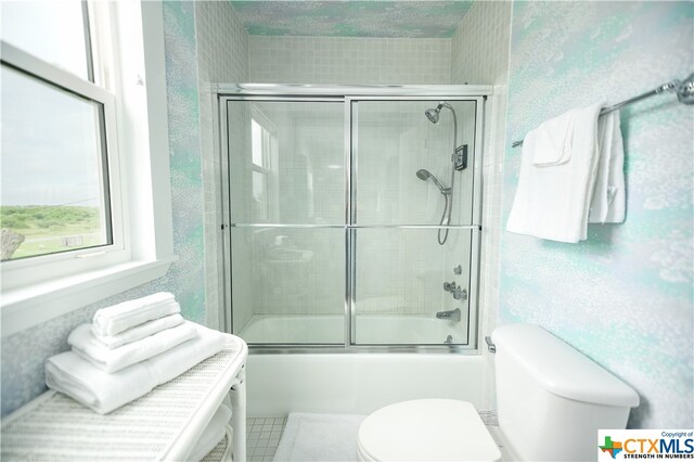 bathroom featuring bath / shower combo with glass door, tile patterned flooring, toilet, and a textured ceiling