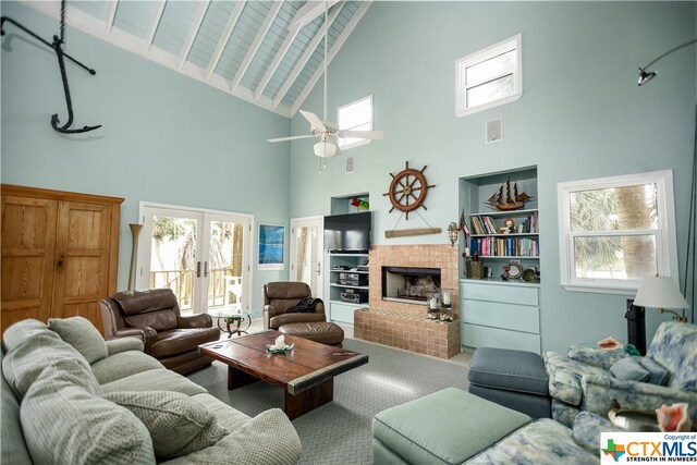 carpeted living room with a brick fireplace, high vaulted ceiling, a healthy amount of sunlight, and ceiling fan