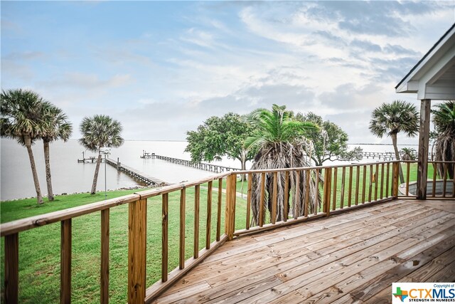 deck with a water view and a lawn