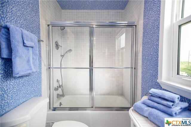 bathroom featuring enclosed tub / shower combo and toilet