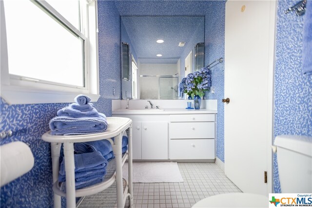 bathroom featuring walk in shower, vanity, a textured ceiling, and tile patterned floors