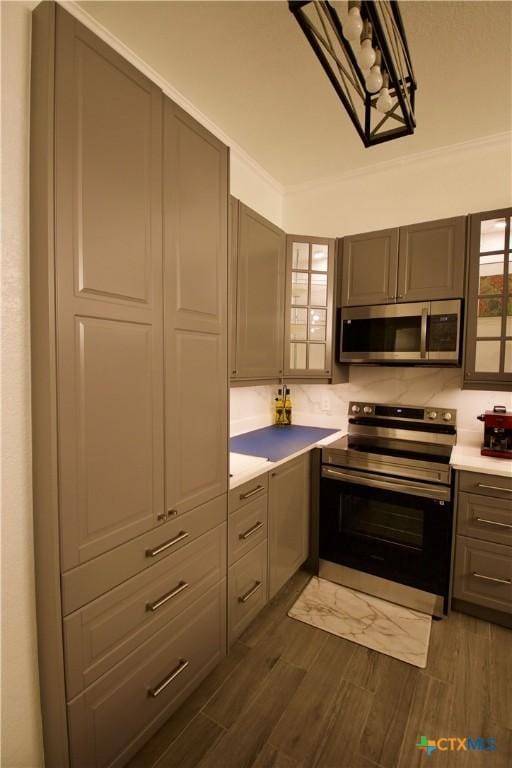 kitchen featuring ornamental molding, appliances with stainless steel finishes, and dark hardwood / wood-style flooring