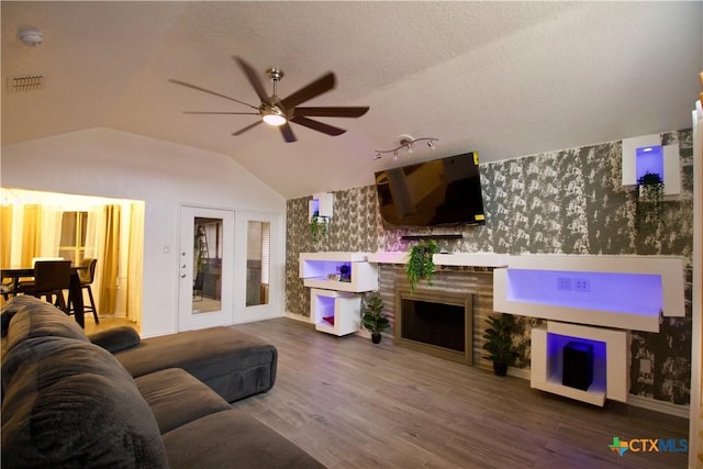 living room featuring hardwood / wood-style flooring, vaulted ceiling, a textured ceiling, and ceiling fan