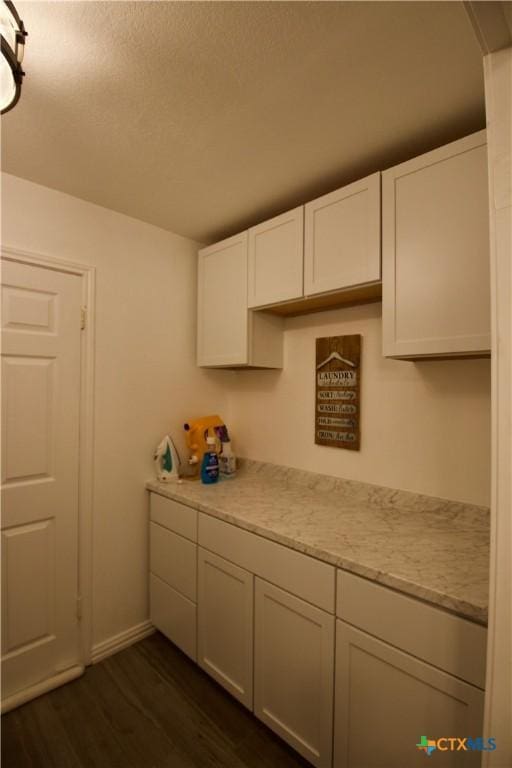 kitchen with white cabinetry, dark hardwood / wood-style flooring, and light stone counters