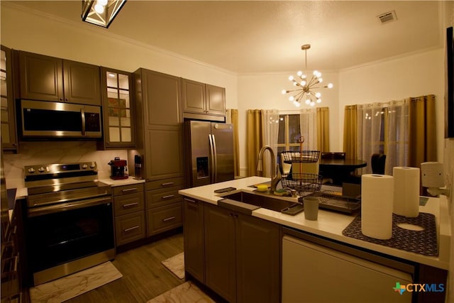 kitchen with crown molding, dark brown cabinets, hanging light fixtures, appliances with stainless steel finishes, and dark hardwood / wood-style floors