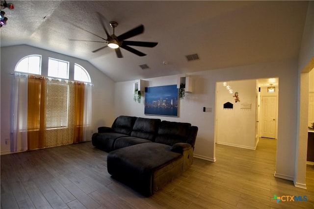 living room with vaulted ceiling, ceiling fan, light hardwood / wood-style floors, and a textured ceiling