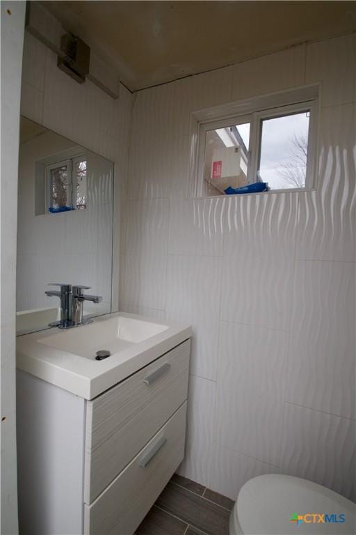 bathroom with vanity, tile walls, and toilet