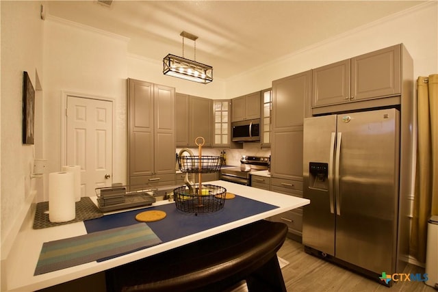 kitchen with gray cabinets, appliances with stainless steel finishes, a breakfast bar area, and pendant lighting