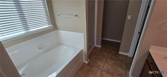 bathroom featuring vanity, a bath, and baseboards