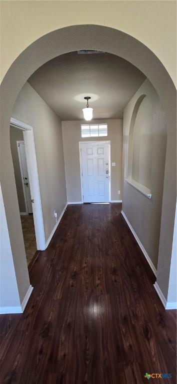 interior space featuring arched walkways, wood finished floors, and baseboards