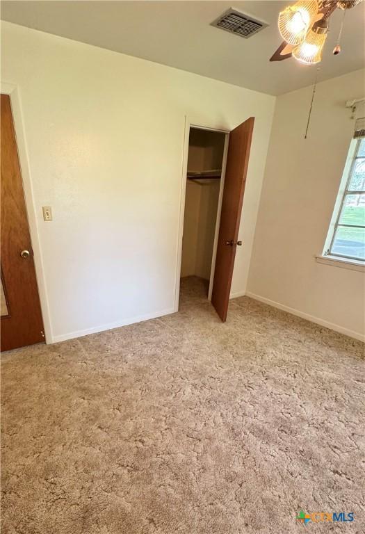 unfurnished bedroom with carpet floors, a closet, baseboards, and ceiling fan