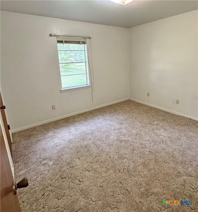 carpeted empty room featuring baseboards