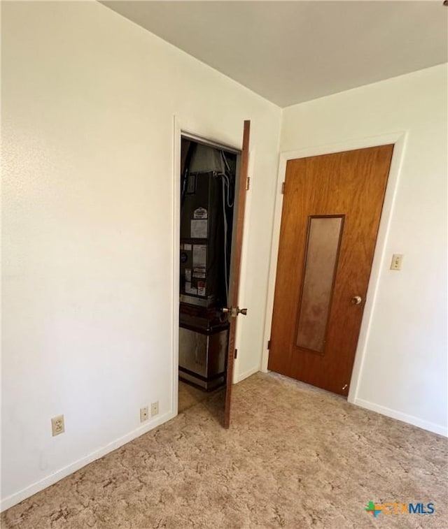 spare room featuring light carpet and baseboards