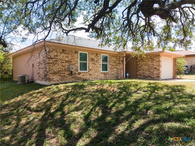 ranch-style house featuring a garage, central AC unit, and a front yard