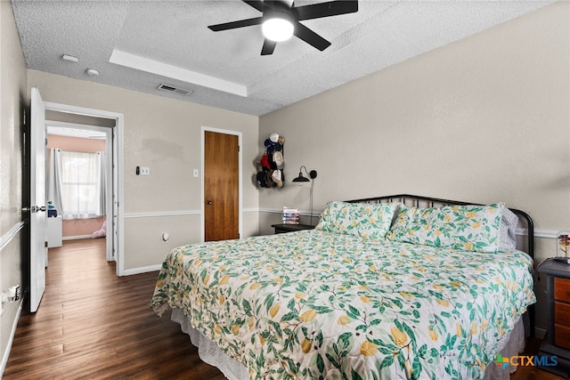 bedroom with dark wood-type flooring, ceiling fan, and a textured ceiling