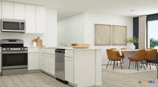 kitchen featuring white cabinetry, a sink, light countertops, stainless steel appliances, and a peninsula