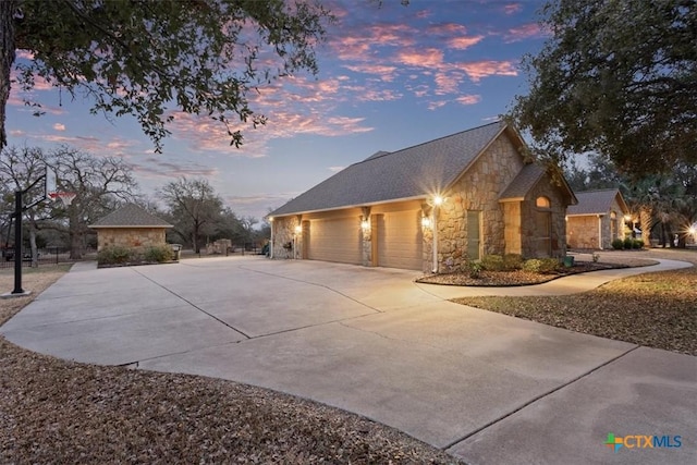 view of front facade featuring a garage, stone siding, and concrete driveway