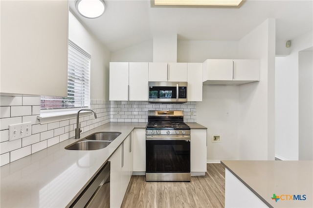 8430 Alvin High Ln, Austin, TX 78729 - kitchen featuring stainless steel appliances, a sink, white cabinets, light wood-style floors, and decorative backsplash
