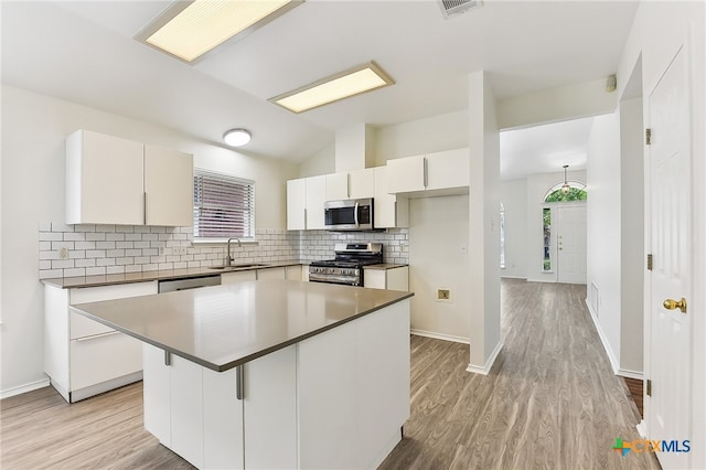 8430 Alvin High Ln, Austin, TX 78729 - kitchen featuring appliances with stainless steel finishes, a sink, decorative backsplash, light wood finished floors, and lofted ceiling